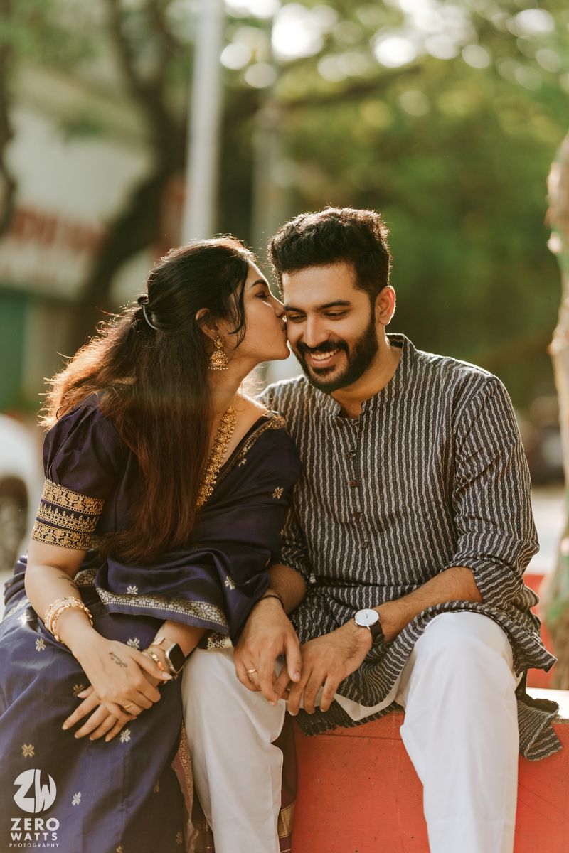 A romantic outdoor photo shoot in warm sunlight featuring a couple sharing an intimate moment on a bench.