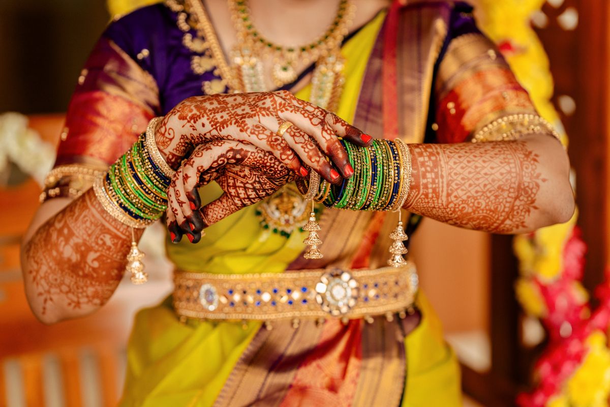 Close-up of traditional Indian bridal hands adorned with intricate mehndi designs and colorful bangles.
