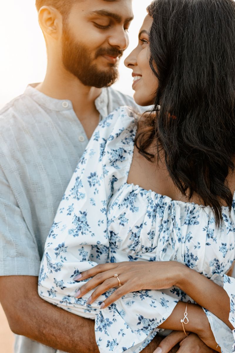 A couple in white and blue outfits share an intimate moment in warm sunlight.