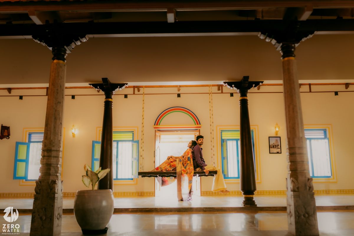 A dancer in an orange dress performs in an elegant indoor space with ornate pillars and high ceilings.
