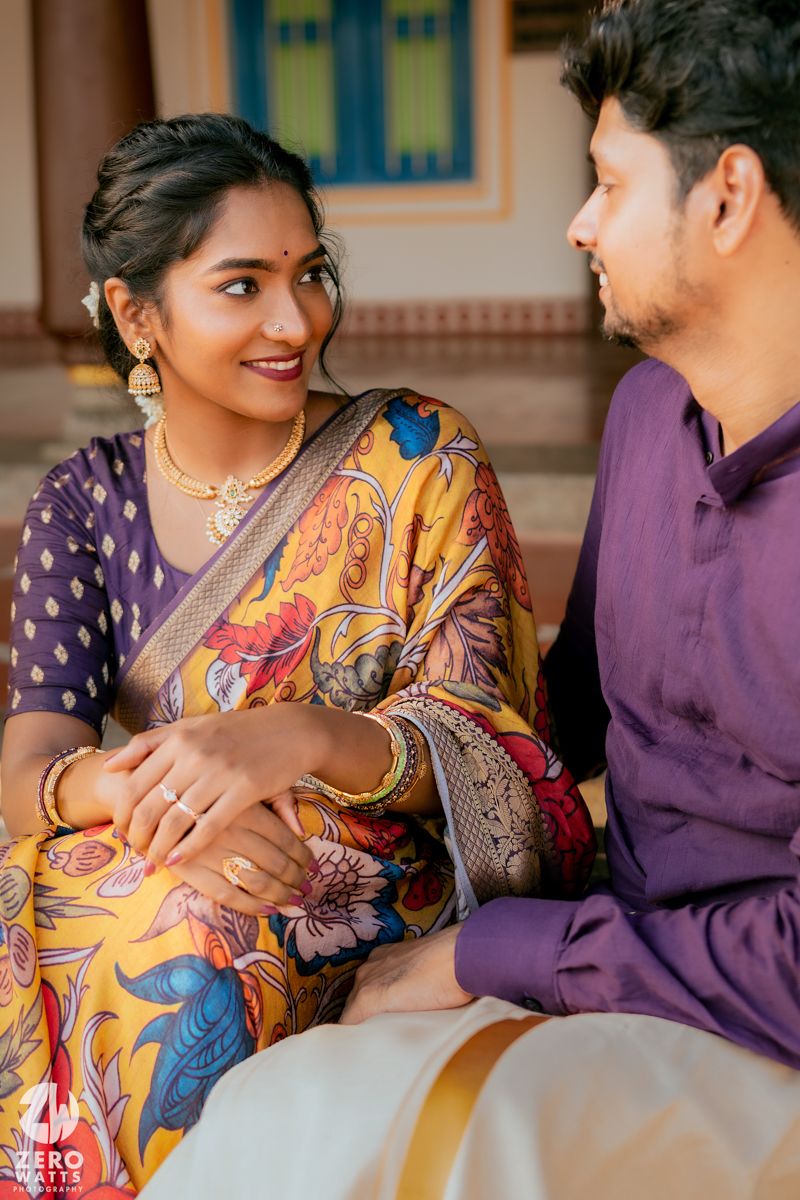A couple in traditional Indian attire share a tender moment on an ornate bench.