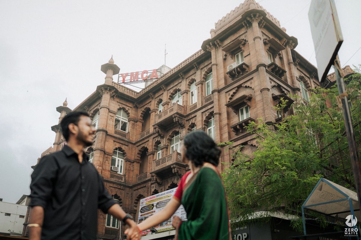 Couple standing in front of historic colonial architecture building in urban setting.