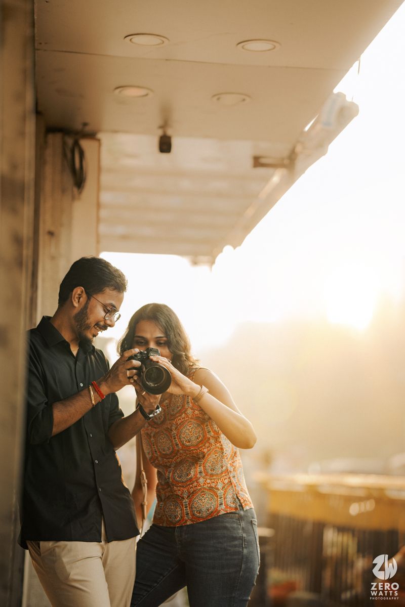 A couple practices photography together during golden hour on a balcony.
