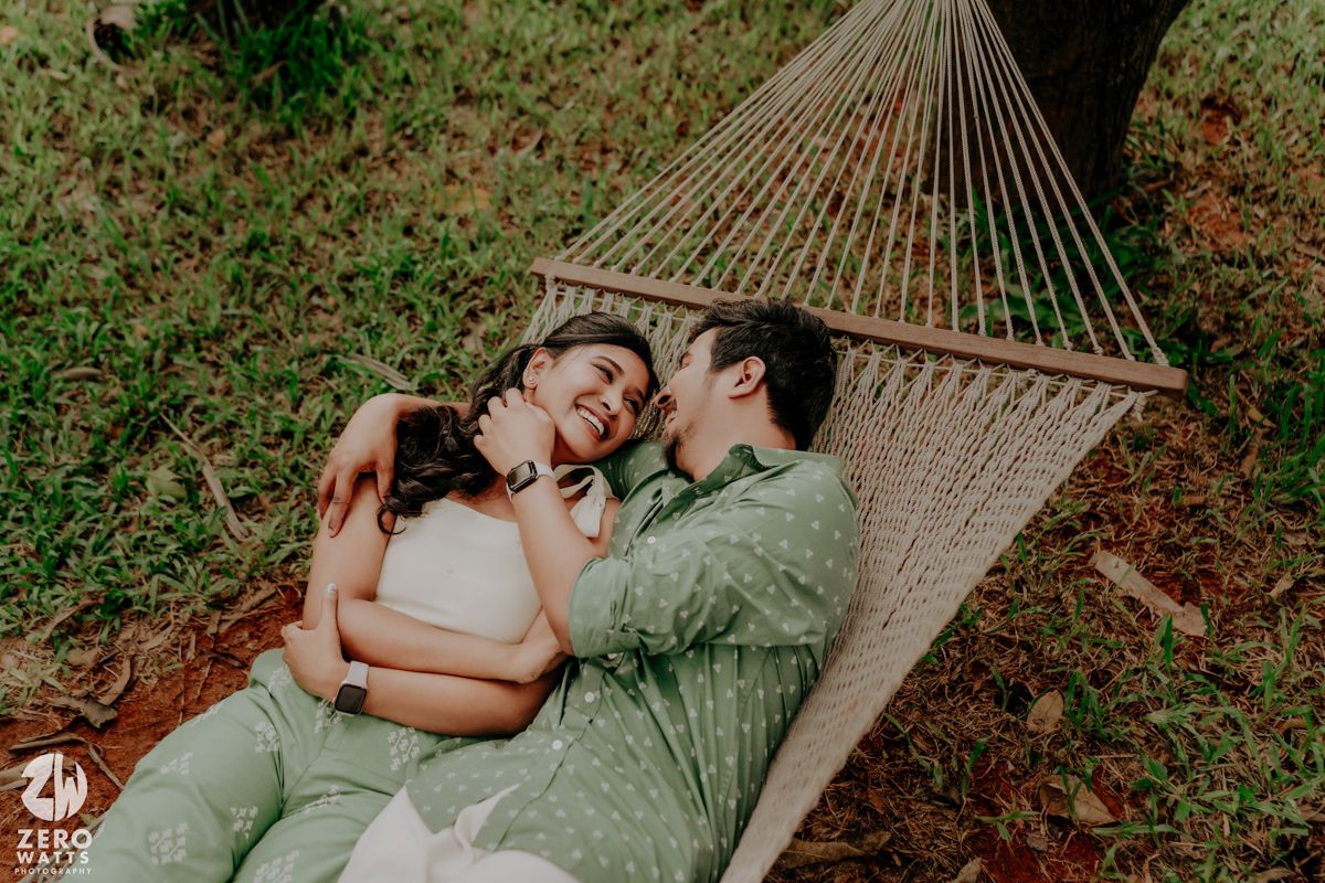 A couple shares intimate moments while relaxing together in a hammock surrounded by greenery.