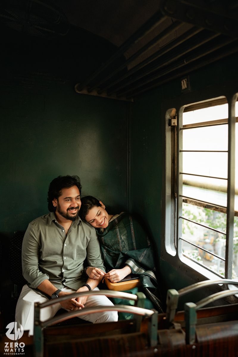 A couple shares quiet moments together on wooden seats inside a dimly lit train compartment.