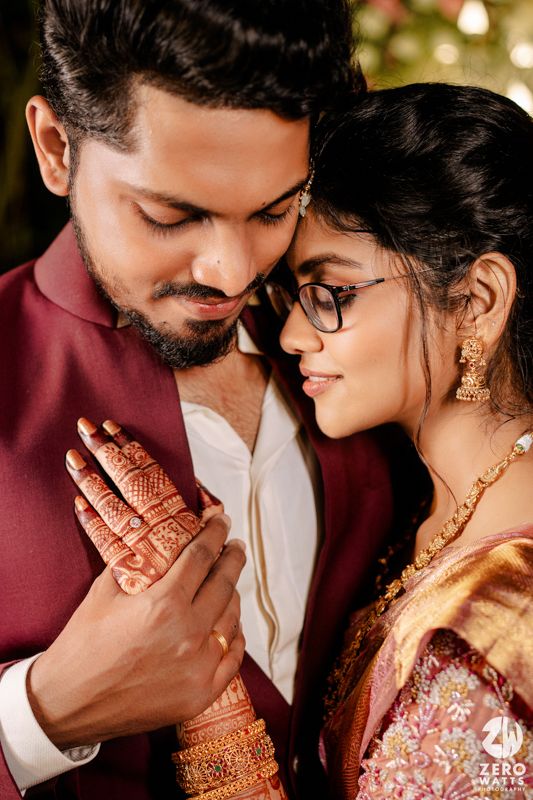 A tender romantic moment captured between a couple wearing traditional Indian wedding clothing and jewelry.