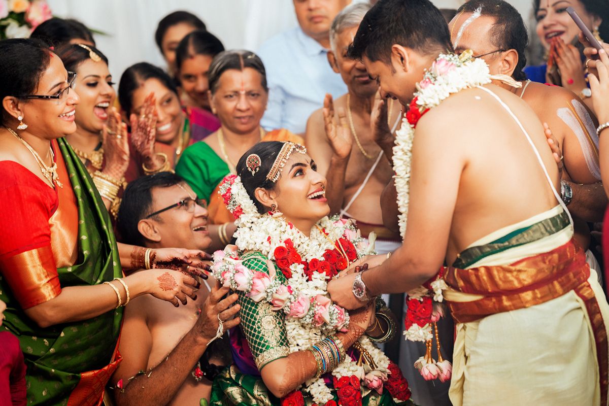 Joyous moment during a traditional Hindu wedding ceremony with family members surrounding the couple.