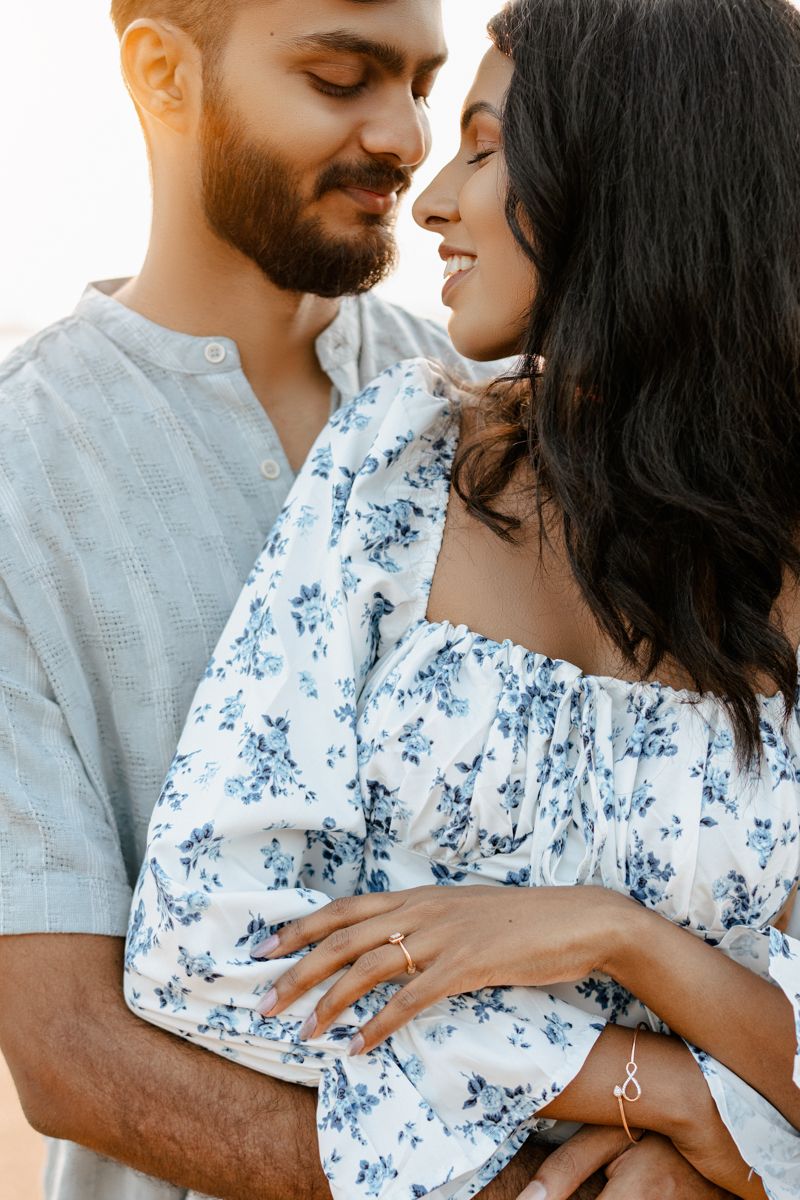 A tender moment between a couple in matching blue and white outfits against a sunlit backdrop.