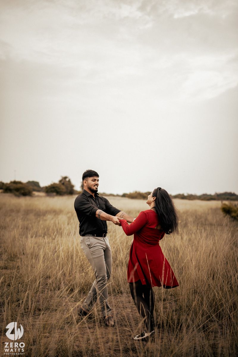 A couple dances together in a golden field during sunset.