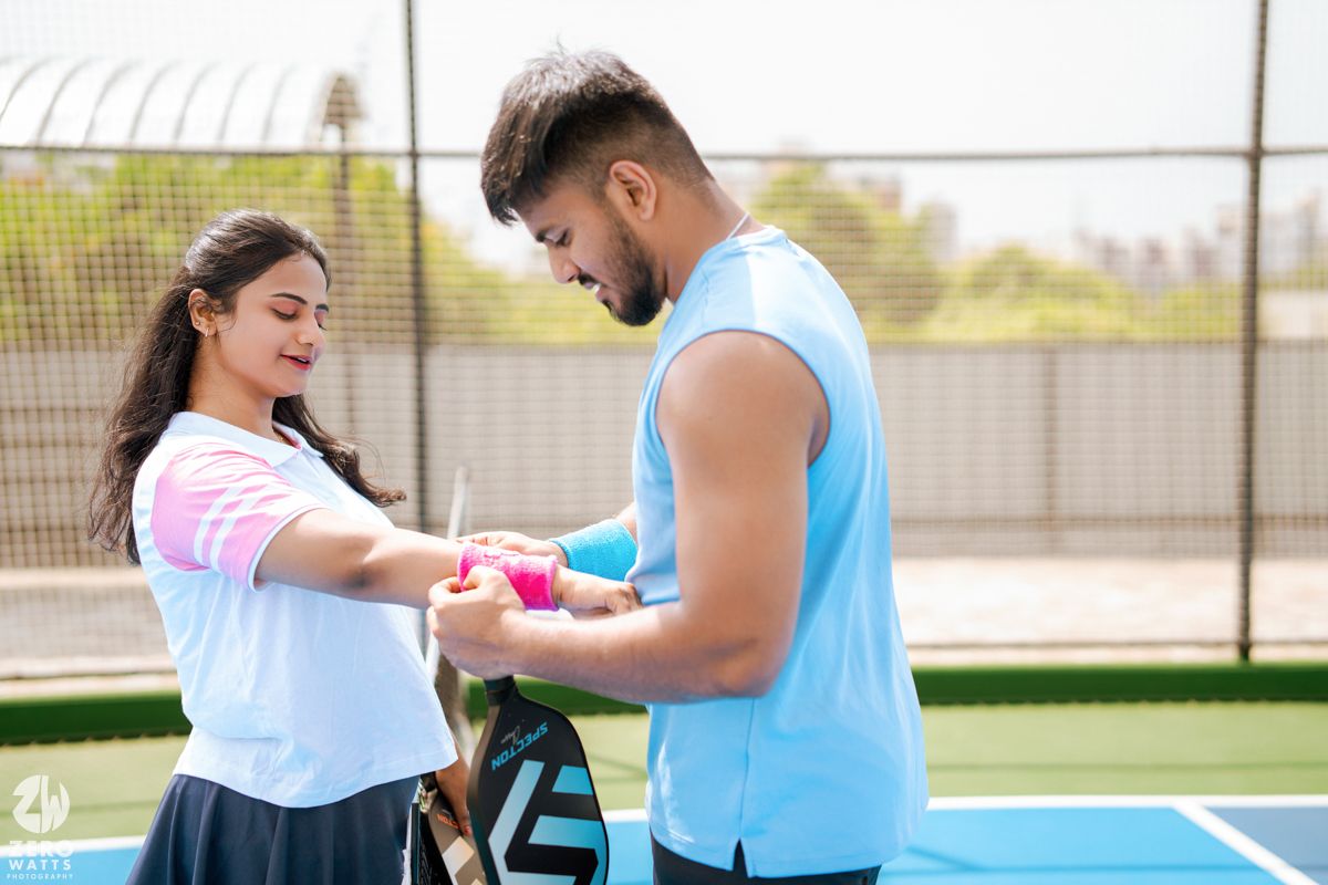 Two people in athletic wear embracing on an outdoor tennis court.