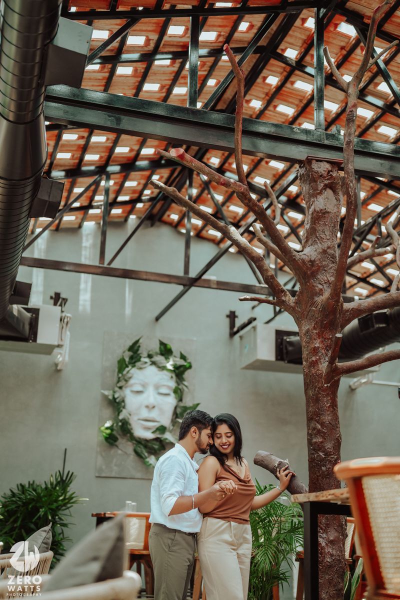 A couple sharing a romantic moment in an indoor venue with exposed wooden beams and artistic decor.