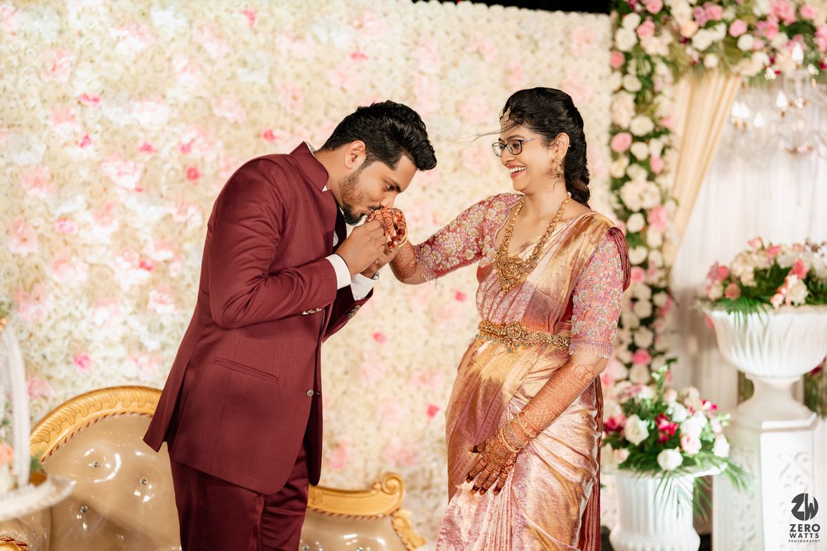 Wedding party performs choreographed poses against a floral backdrop in maroon and blush pink colors.