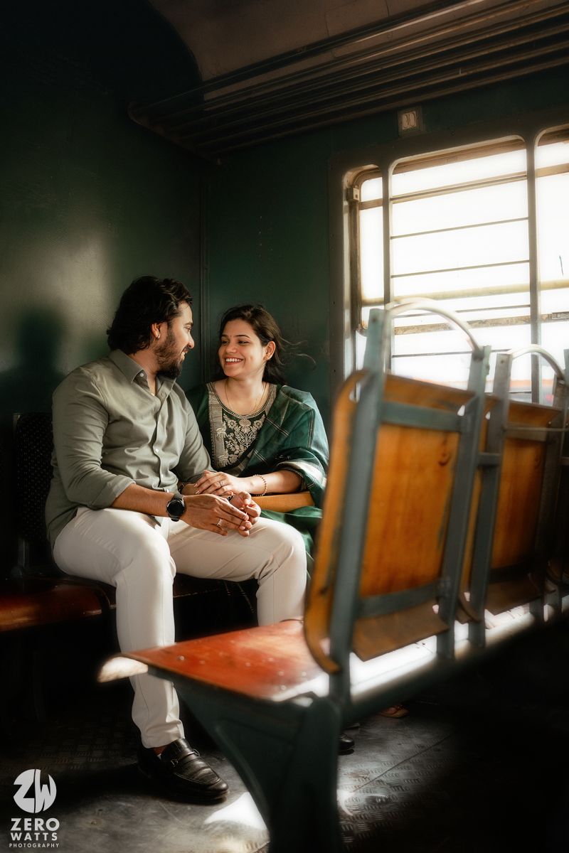 A romantic photoshoot in a vintage train car with dramatic shadows and sunlight streaming through windows.