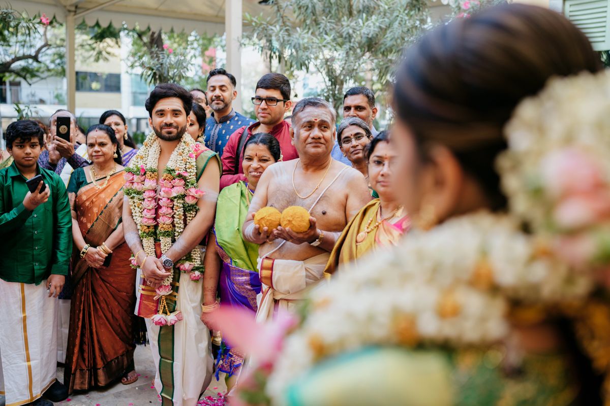 Guests wearing vibrant traditional Indian attire gather at a cultural celebration with decorative elements and flowers.