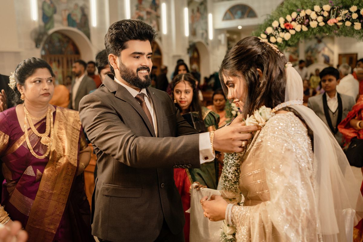 A traditional wedding ceremony takes place inside a church decorated with pink floral arrangements.