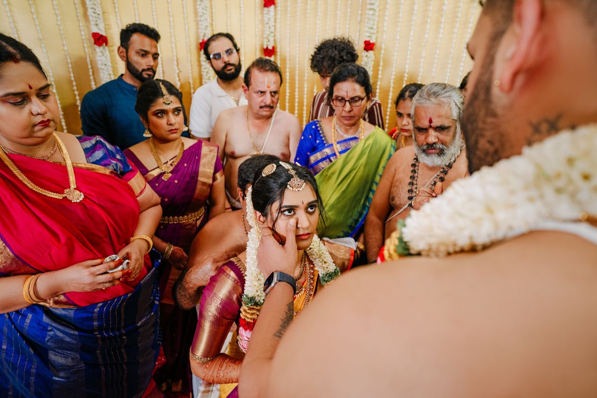 Joyous wedding celebration with guests gathered for traditional Indian ceremony indoors.