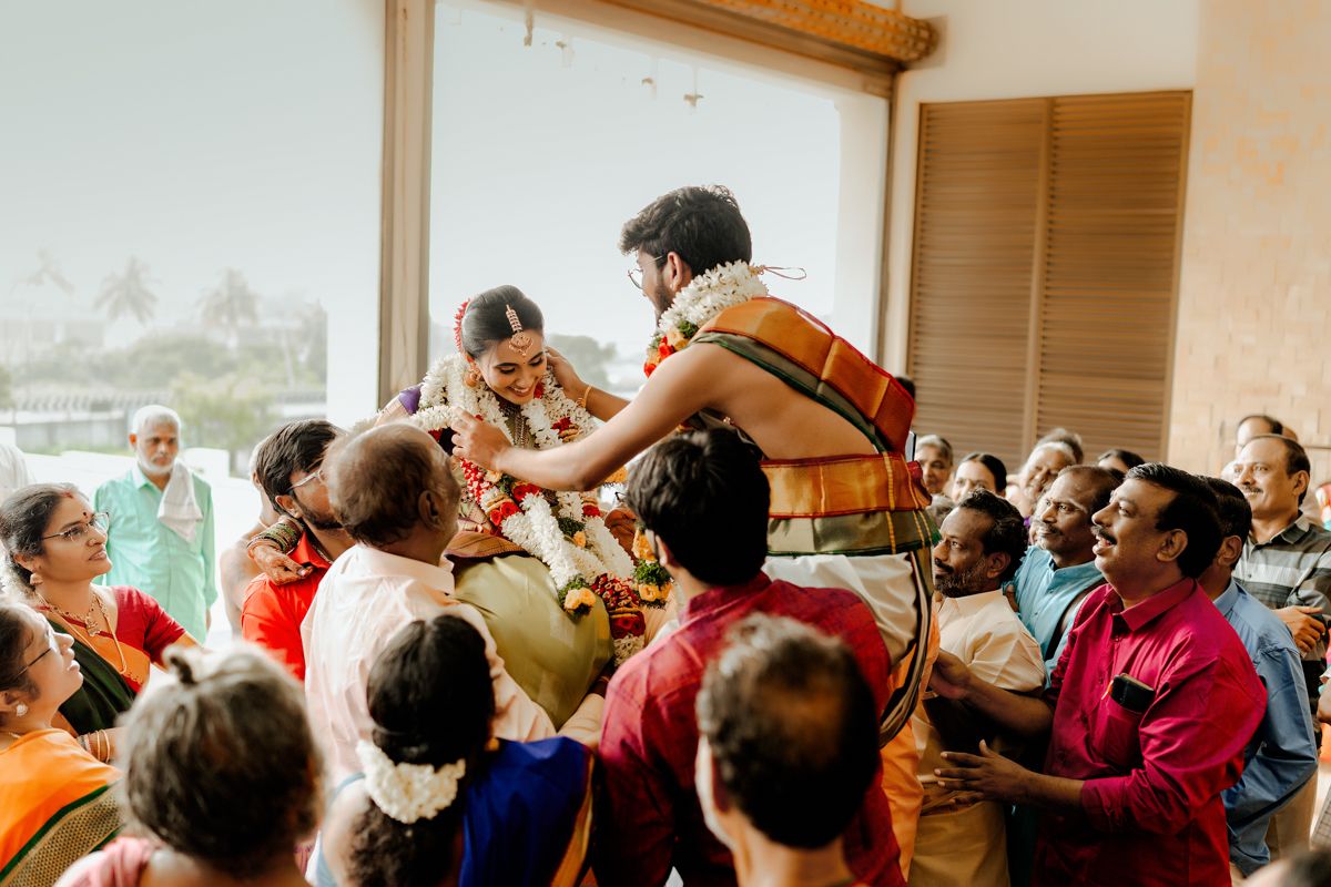 Energetic wedding celebration with guests lifting and supporting participants during a traditional ceremony.