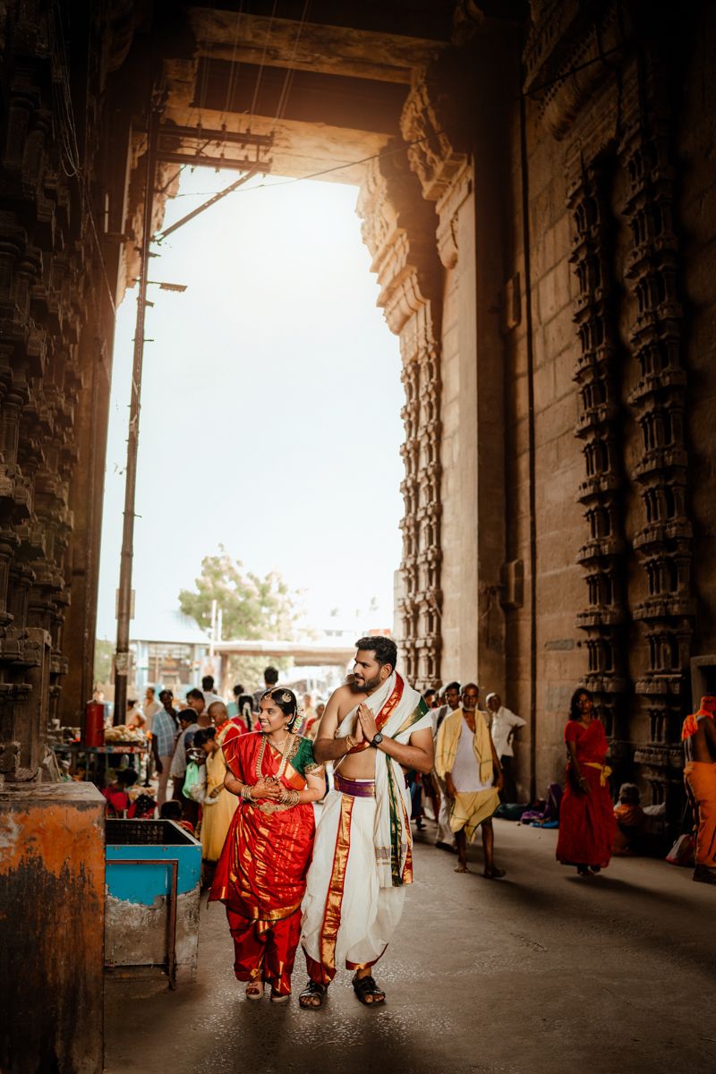 Traditional Indian temple corridor with visitors walking through the ornate stone architecture.