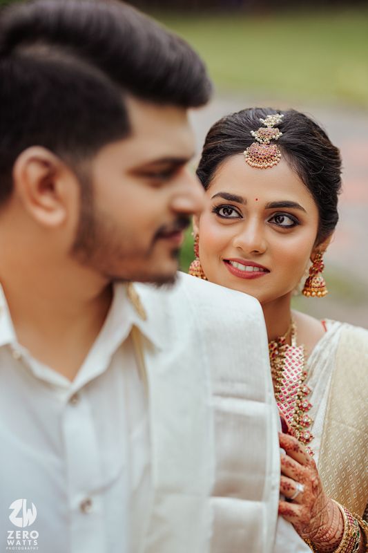 Wedding couple shares intimate moments during their South Indian ceremony wearing traditional white and gold attire.