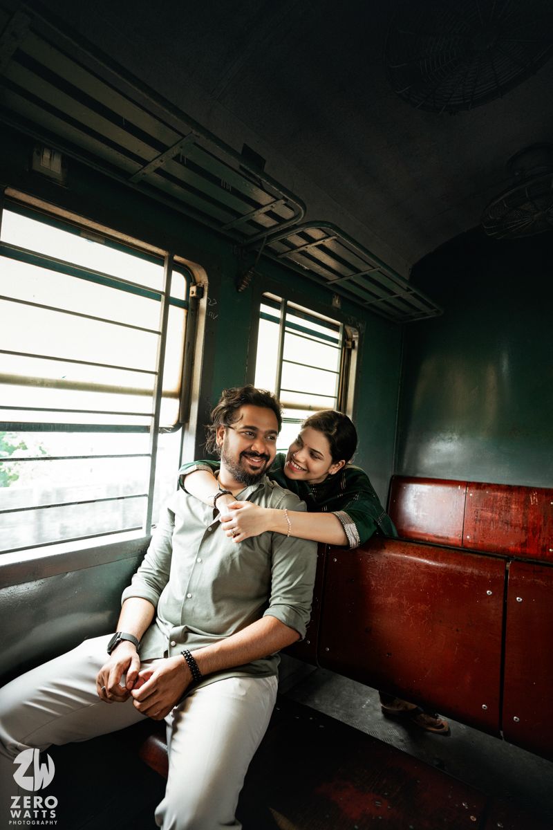 Two passengers share an intimate moment while sitting together on a train during a journey.