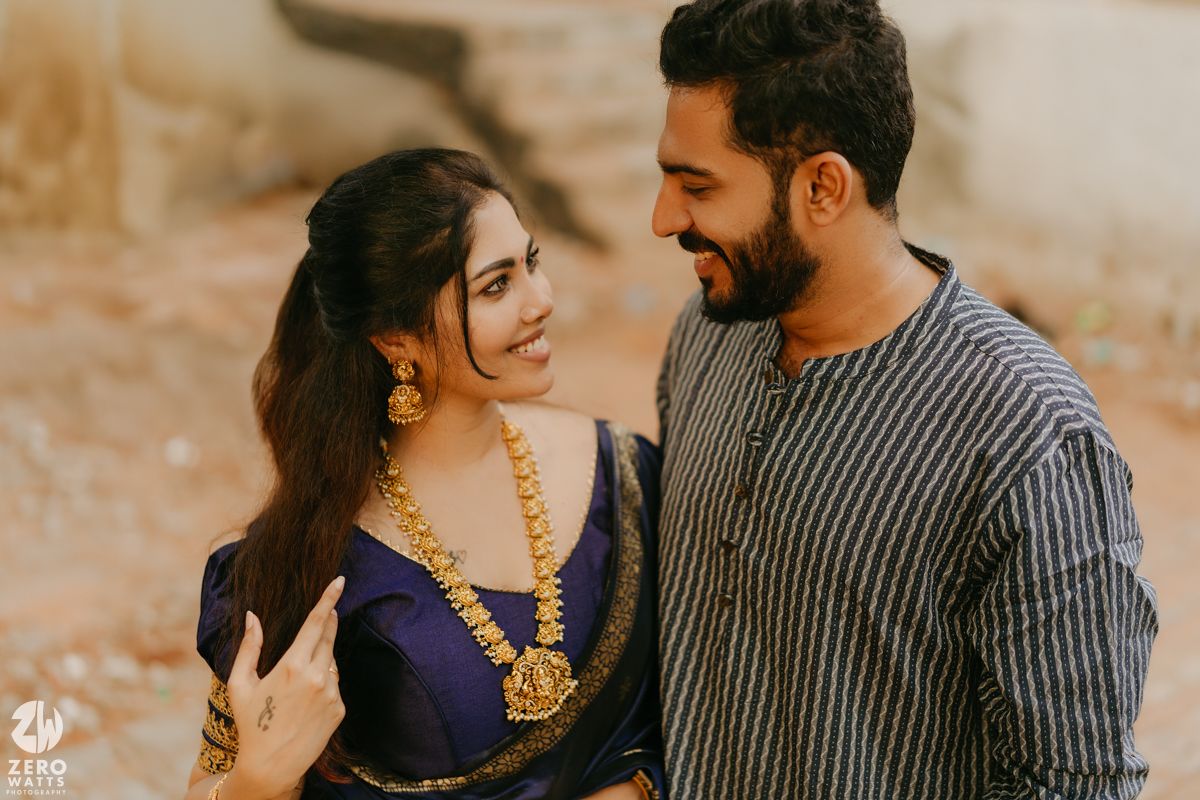 A romantic couple in traditional Indian attire share intimate moments during a golden hour photo session in a rustic setting.