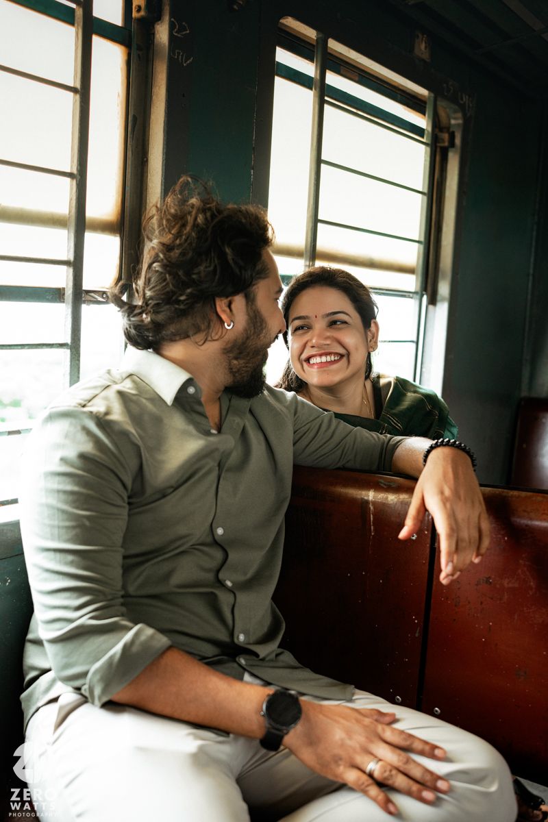 Two people share an intimate moment while sitting together in a train car with sunlight streaming through the windows.