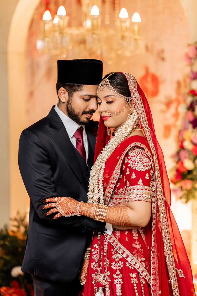 Wedding scene with traditional formal attire and elaborate floral decorations under chandelier lighting.