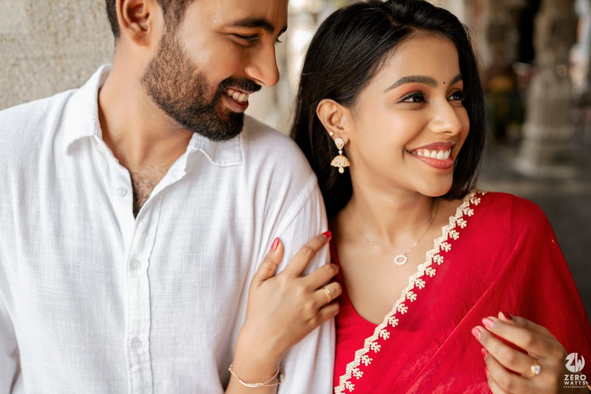 Close up shot of couple in traditional Indian attire sharing an intimate moment under temple pillars.