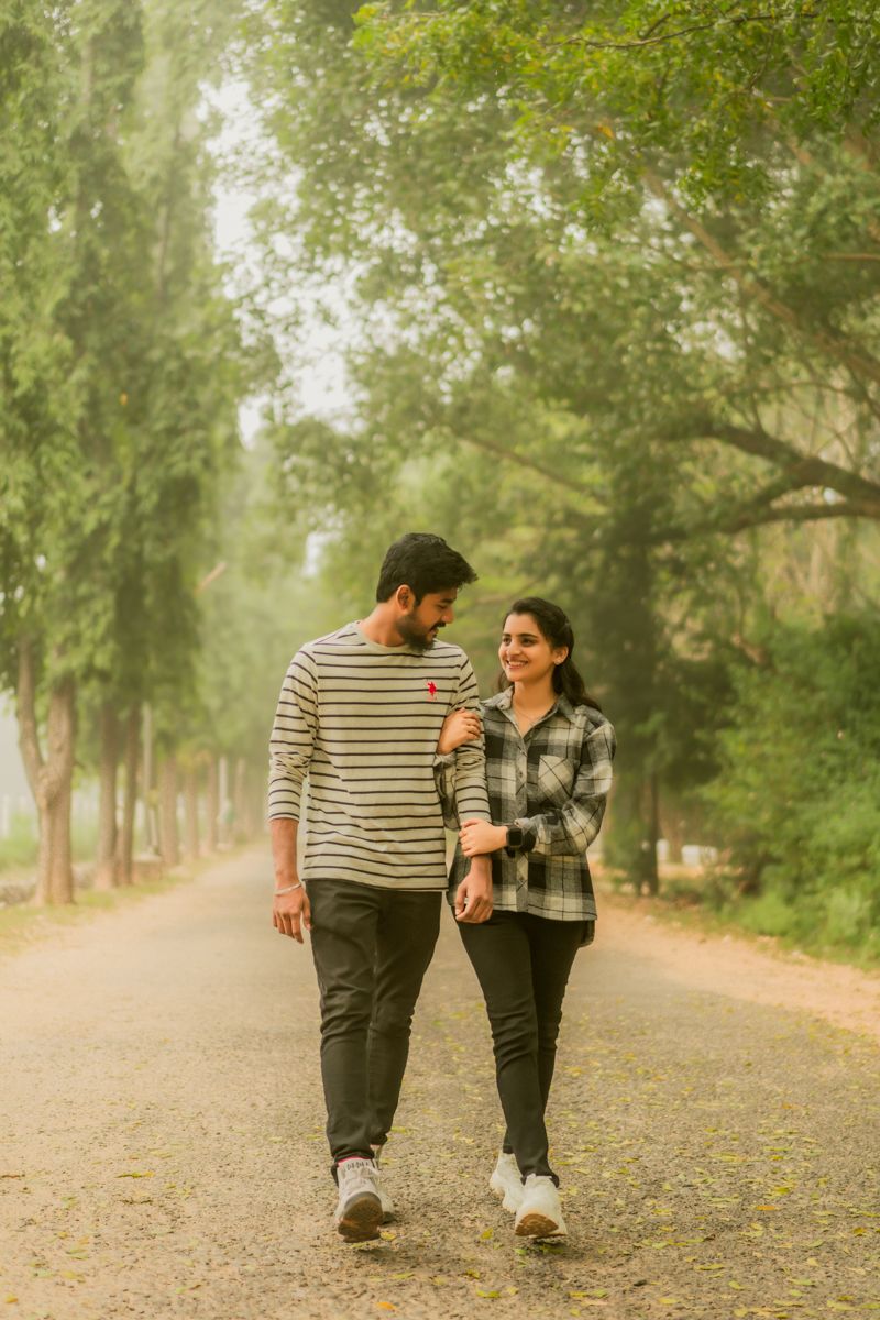 Couple walking together on tree-lined path during autumn.