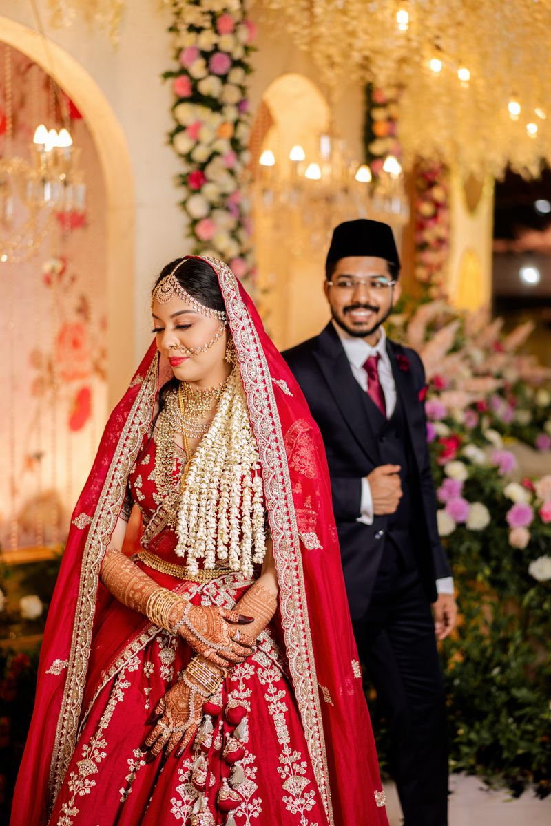Traditional South Asian wedding ceremony with elegant floral decor and arched golden backdrop.