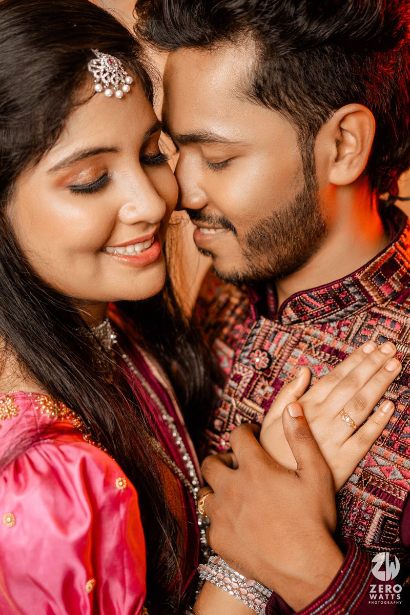 A romantic moment captured between a couple in traditional Indian attire with detailed embroidery and jewelry.