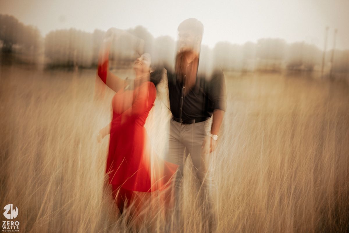 Motion blur capture of a couple dancing in a wheat field with dramatic lighting.