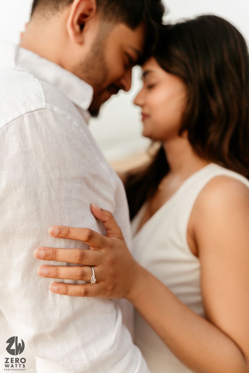 Intimate couple dressed in white sharing tender moments during studio photography session.