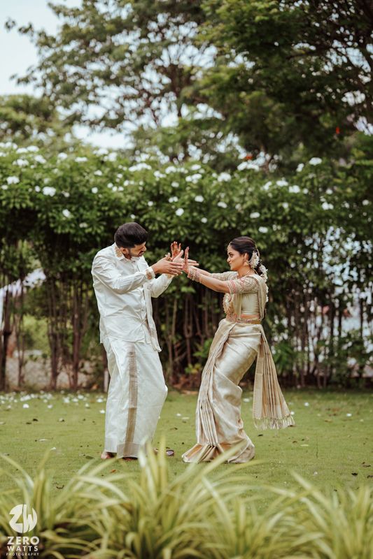 Couple engaging in playful dance poses on a grassy lawn.