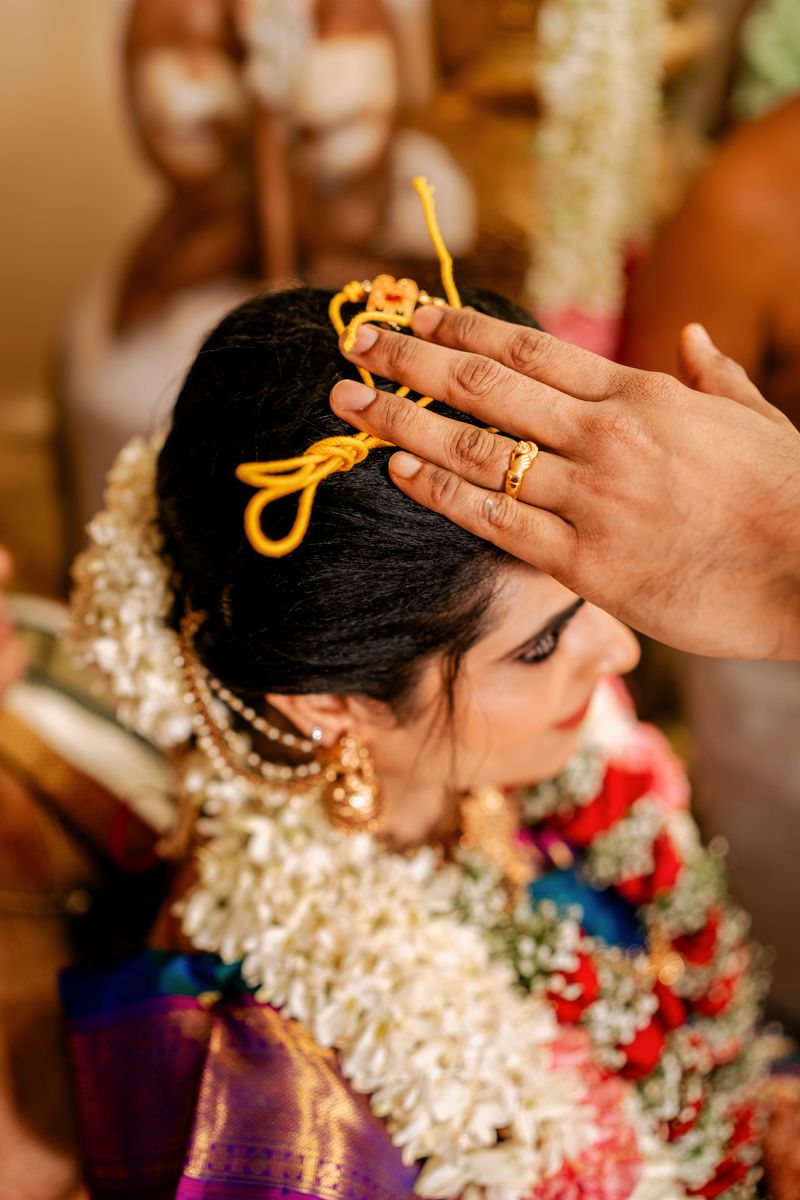 Close-up of traditional South Indian bridal jewelry and floral decorations during wedding ceremony.