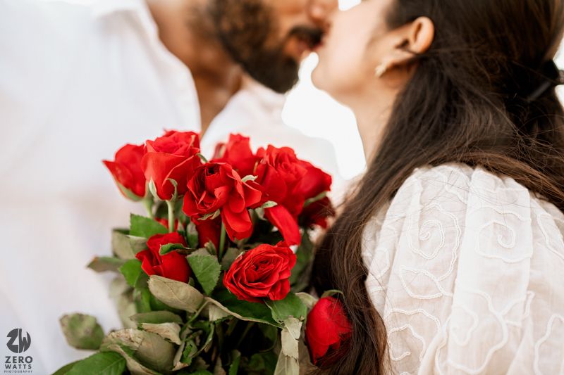 Close up photograph with red roses bouquet and couple sharing an intimate moment.