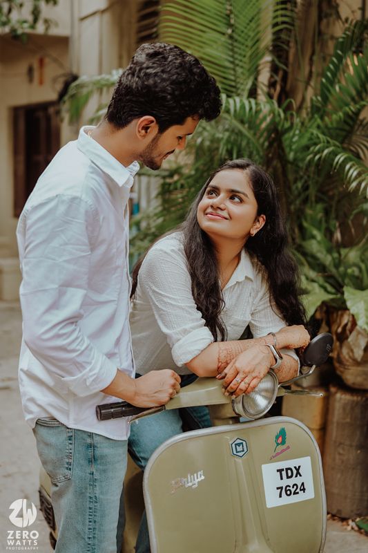 Sweet interaction near a vintage scooter surrounded by tropical plants.