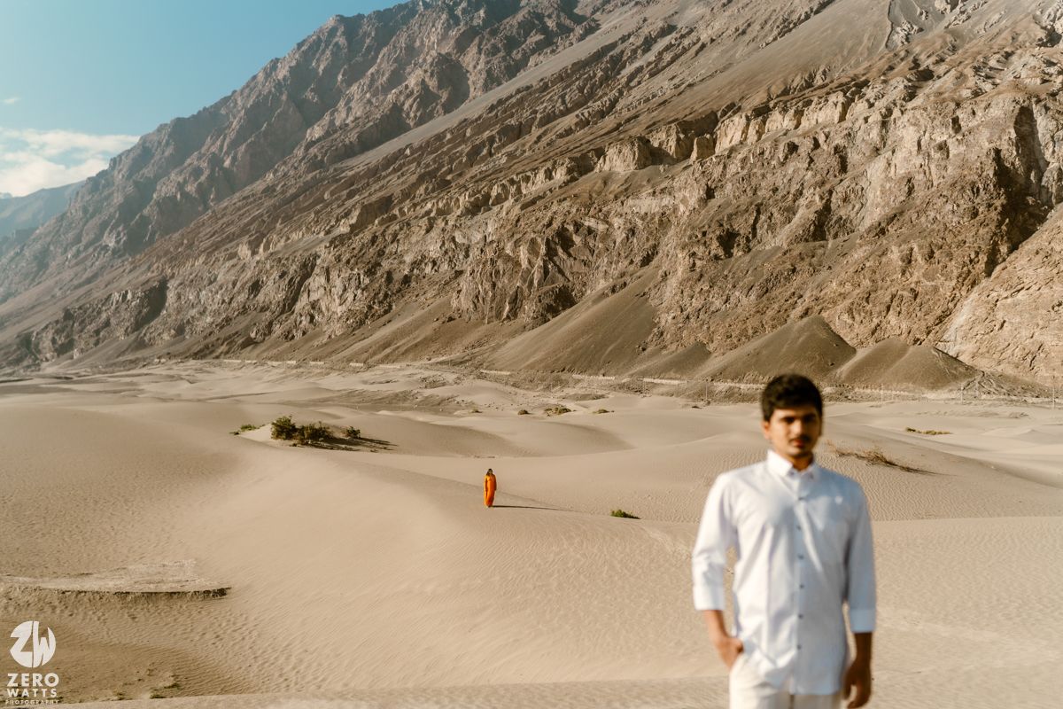 Panoramic view of a majestic mountain landscape with barren slopes and winding road through rugged terrain.