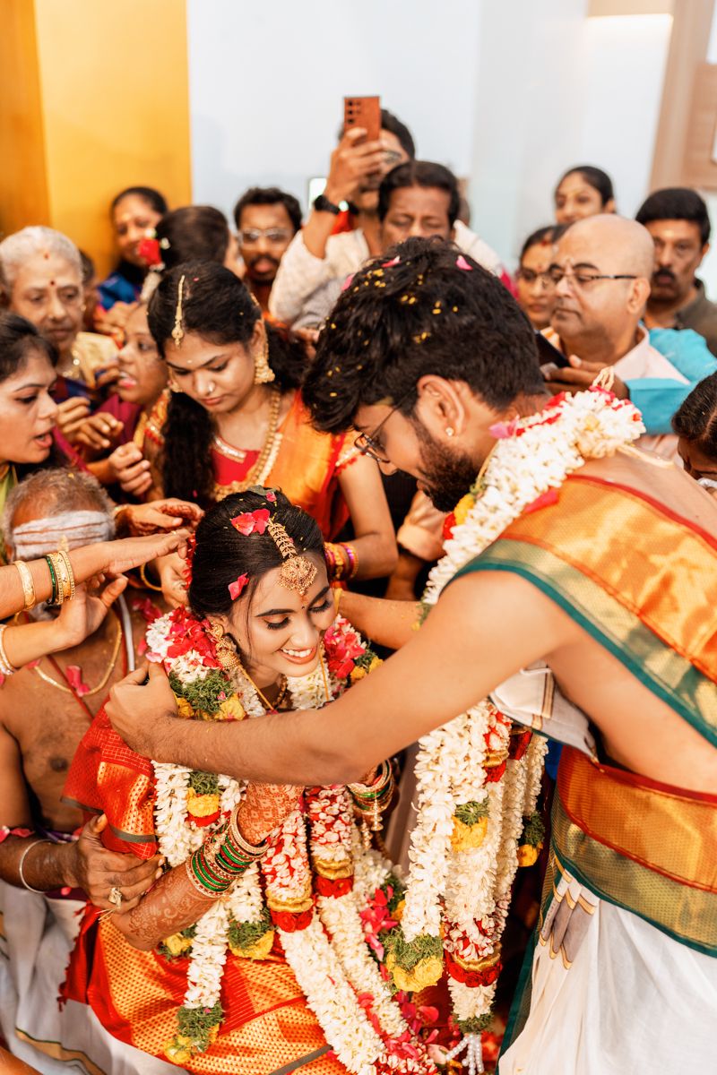 Traditional South Indian wedding ceremony with participants wearing colorful silk sarees and flower garlands during a ritual.