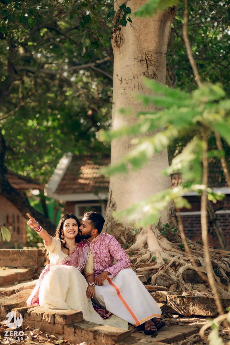 Couple sitting under a large tree sharing an intimate moment in traditional Indian attire.