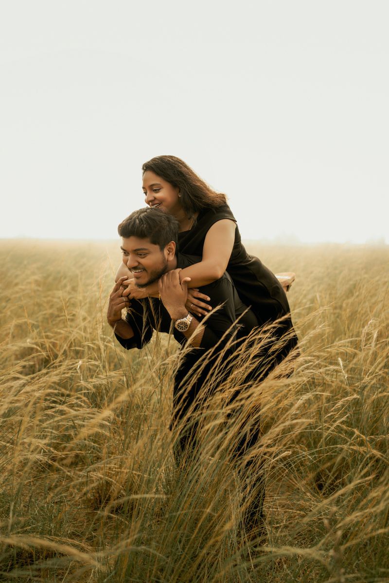 Playful couple having fun in a wheat field with piggyback ride.