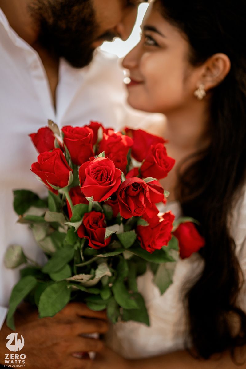 A tender moment shared between a couple with vibrant red roses in the foreground.