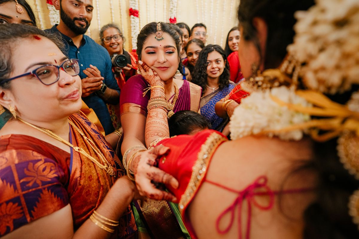 Wedding guests participate in a traditional Indian ceremony ritual wearing vibrant red and gold attire.