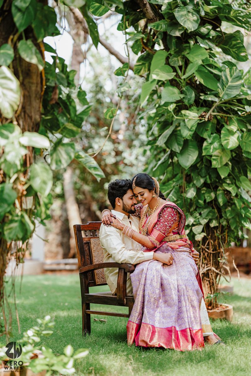Romantic couple moment on wooden bench under lush green garden foliage.