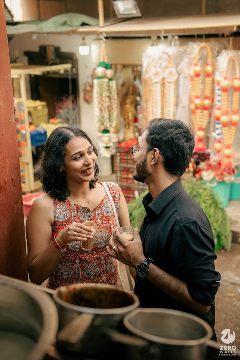 A couple enjoying conversation at a colorful Indian market stall with festive decorations.