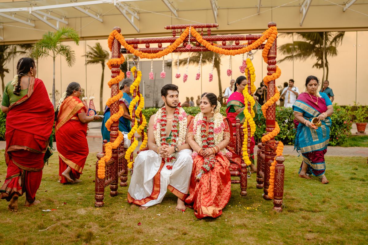 Traditional South Indian wedding ceremony under a decorated mandap with colorful floral and fabric arrangements.