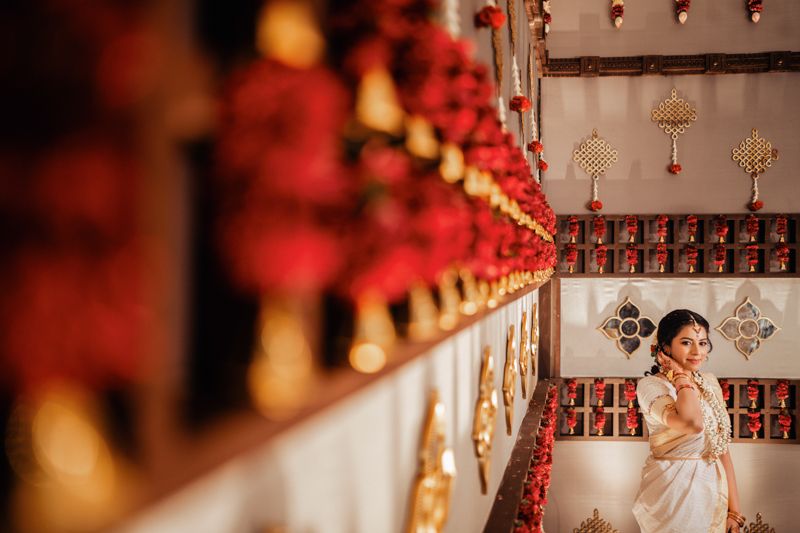 Artistic wedding photo with traditional decor featuring red lanterns and metallic ornaments.