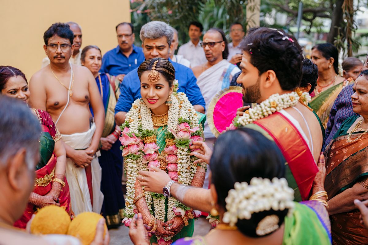 Wedding guests participating in a traditional ceremony with flower garlands and festive attire.