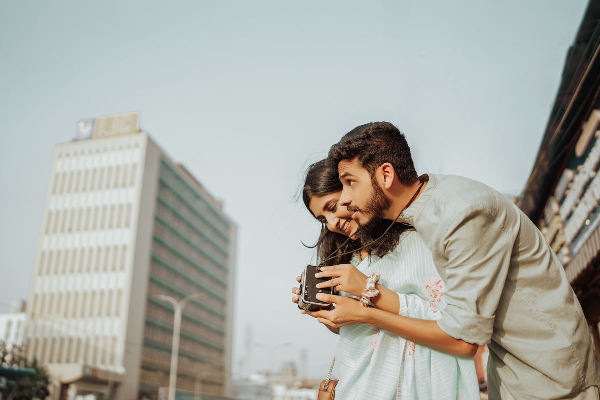 A romantic vintage-inspired photoshoot with a retro camera against an urban backdrop of tall buildings.