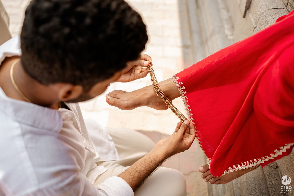 Close up detail shot of decorative border work on a bright red saree against white traditional clothing.